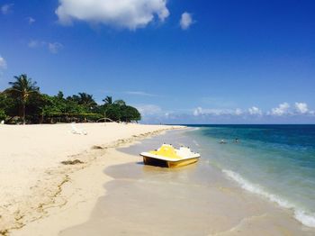 Pedal boat on shore at beach against sky