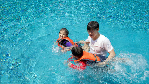 Father with kids playing in swimming pool