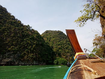 Boat sailing on river by trees against sky