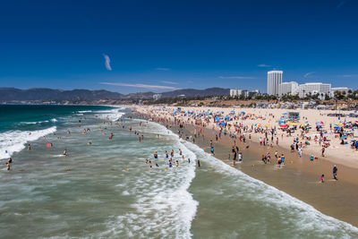 People at beach against blue sky
