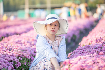 Portrait of woman standing amidst flower plants on field
