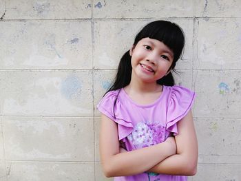 Portrait of a smiling girl standing against wall