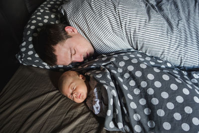 High angle view of father and baby sleeping on bed at home
