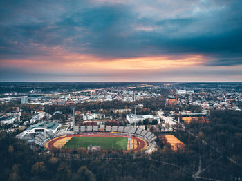 Aerial view of cityscape against cloudy sky during sunset