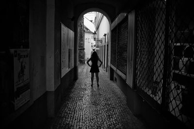 Rear view of silhouette man walking in alley amidst buildings