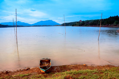 Boat moored on lake against sky