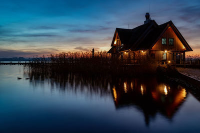 Scenic view of lake by building against sky during sunset