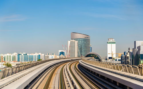 Railroad tracks amidst buildings in city against sky