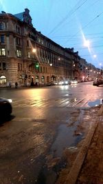 Illuminated city by street against sky