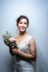 Portrait of young woman holding flower bouquet