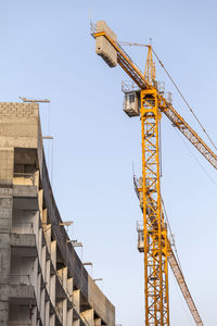 Low angle view of crane against sky