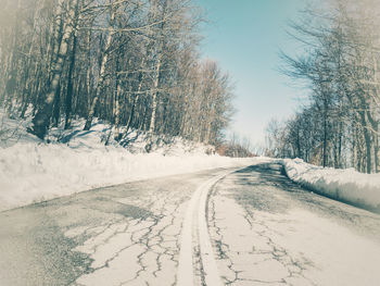 Road amidst snow covered trees against sky