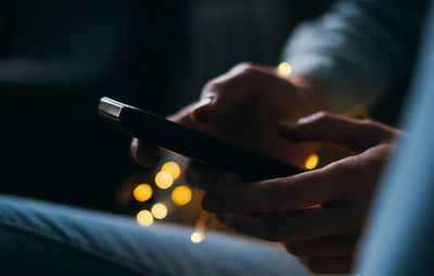 Cropped image of person using phone at night