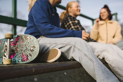 Teenage girls with skateboard sitting in skatepark