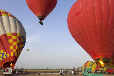 Hot air balloons flying over field against sky