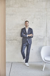 Laughing businesssman standing at concrete wall