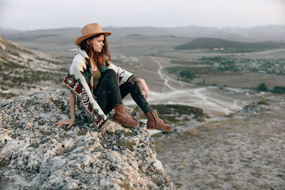 Side view of woman sitting on rock