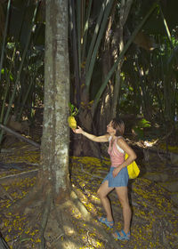 Full length of woman with arms raised on tree