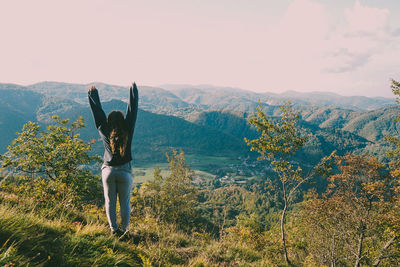 Rear view of woman standing against landscape and sky