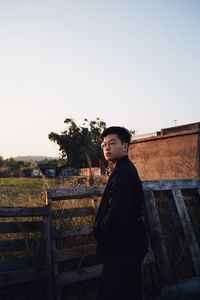 Side view of young man looking away against clear sky