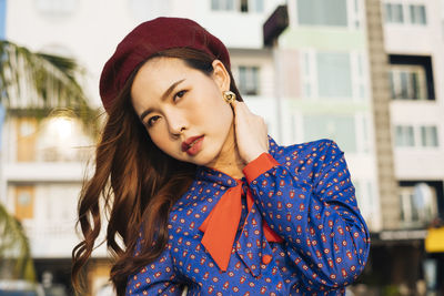 Portrait of young woman standing against buildings