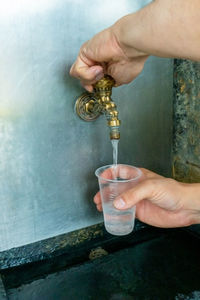 Pouring mineral thermal water into the disposable cup at the pump-room, close-up