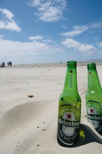 Close-up of beer bottle on beach against sky