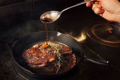 Midsection of person preparing food in cooking pan