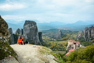 Rear view of woman sitting on rock formation