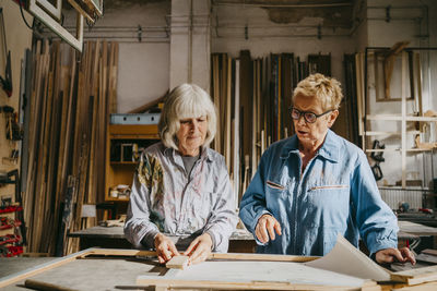 Senior female carpenters discussing with each other while working at workshop