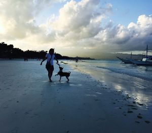 People on beach against cloudy sky
