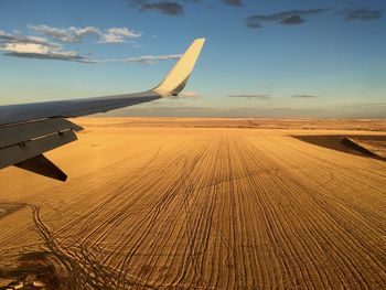 Airplane flying over sand dune in desert against sky