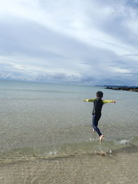 Full length of boy on beach against sky