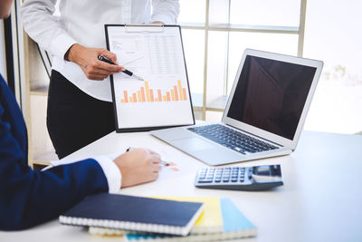 Midsection of colleagues working at desk in office