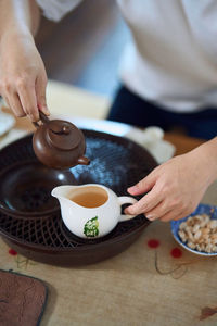 Close up of hands pouring tea from teapot to teacup in a traditional asian tea chamber