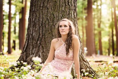 Portrait of young woman in tree trunk in forest