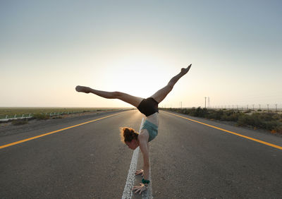 Rear view of man running on road against clear sky during sunset