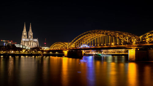 Illuminated bridge over river at night