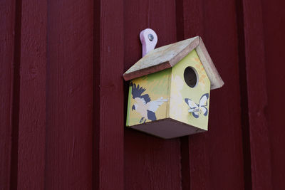 Beautifully decorated birdhouse hung on a red wooden wall in roback