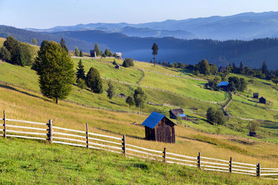 Trees and houses on field against mountains