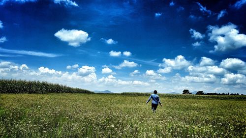 Man standing on field against blue sky