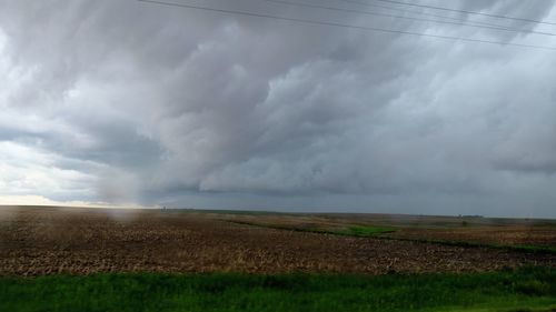 Scenic view of field against storm clouds