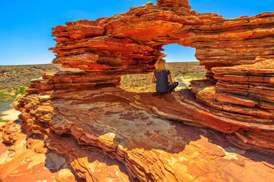Rear view of woman sitting on rock formation at kalbarri national park 