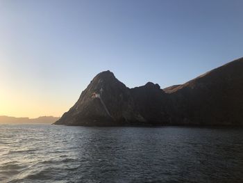 Scenic view of sea and mountains against clear sky