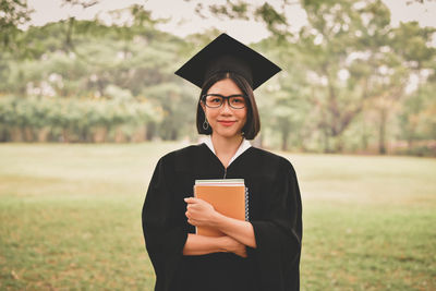 Young woman in graduation gown holding books