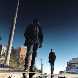 Low angle view of men standing against clear sky