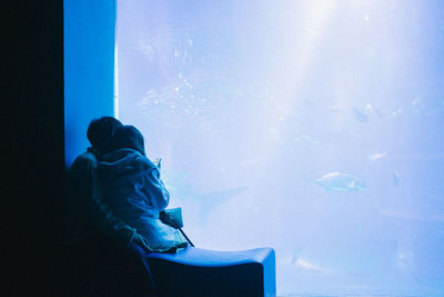 Rear view of man sitting in aquarium