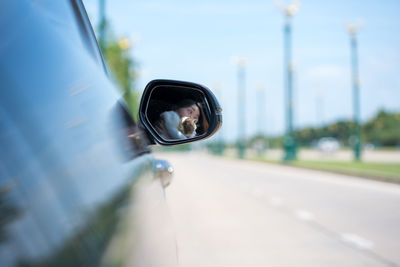 Reflection of man on side-view mirror