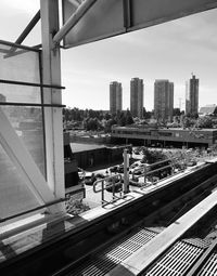 Railroad tracks by buildings against sky seen through glass window