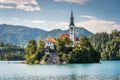 Scenic view of building by trees and mountains against sky